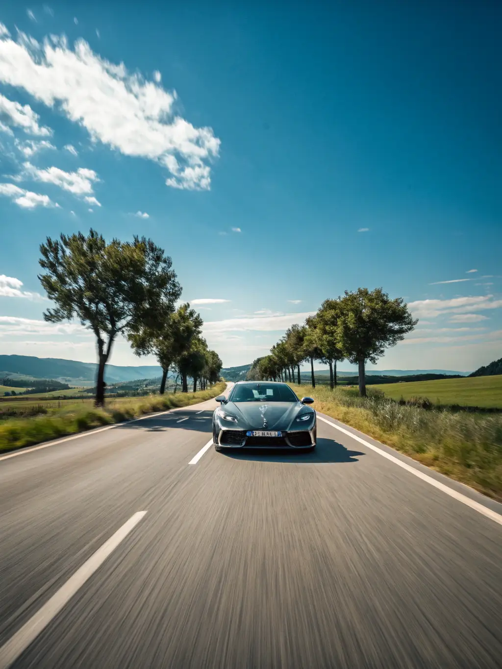 An image depicting a car driving through a scenic German landscape with wind turbines in the background, symbolizing the reduced environmental impact of digital vignettes from gooddigitalsticker.de.